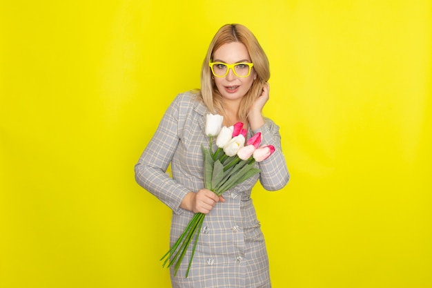 Blonde woman in plaid dress holding tulips bouquet