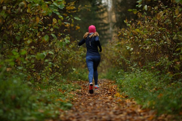 Blonde woman running on trail in autumn park