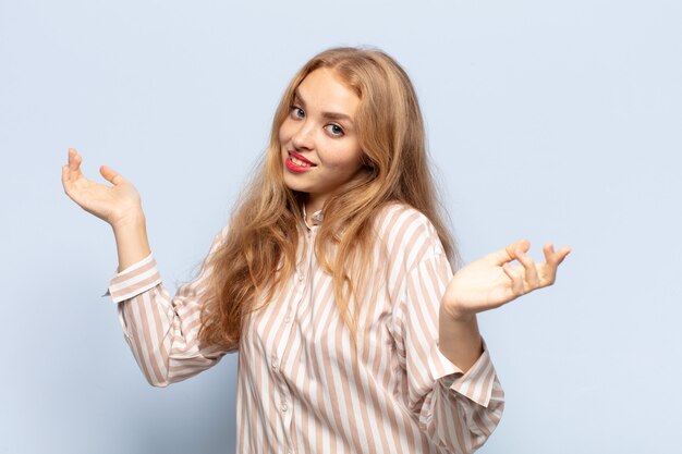 Blonde woman shrugging with a dumb, crazy, confused, puzzled expression, feeling annoyed and clueless