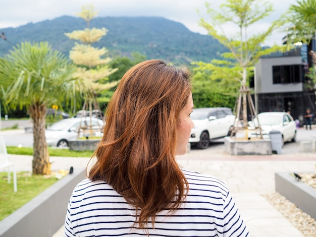 Blonde woman standing backwards and look right in park garden.