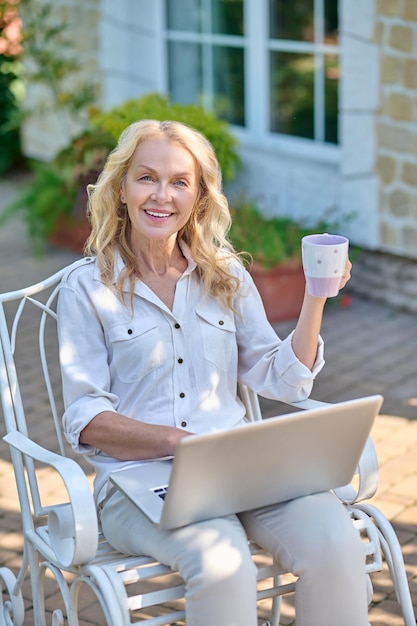 Blonde woman surfing internet while having her morning coffee