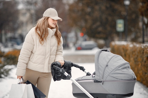 Blonde woman with baby stroller walking in the city with shopping packages