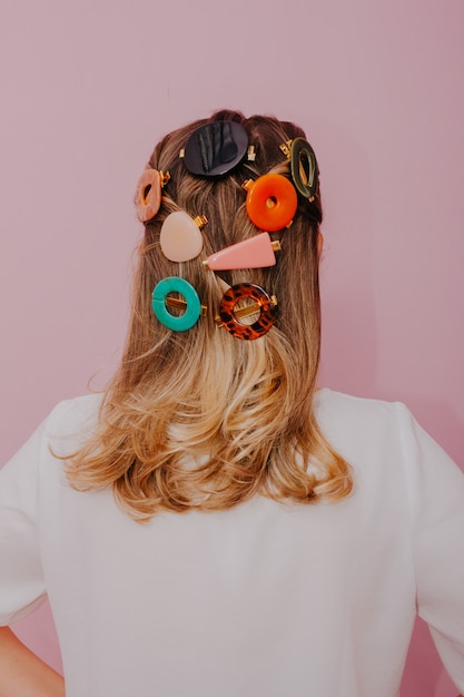 Photo blonde woman with clips in her hair, modern hair pins, pink wall