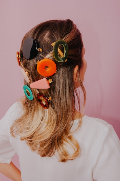 Blonde Woman with Clips in her hair, modern hair pins, pink wall