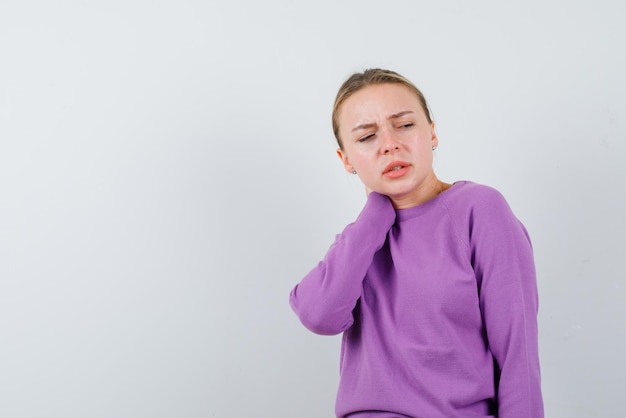 The blonde woman with neckache is looking back on white background