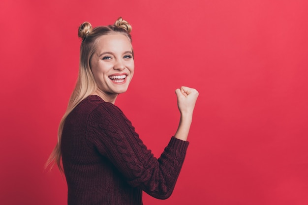 blonde woman with top-knots posing against the red wall