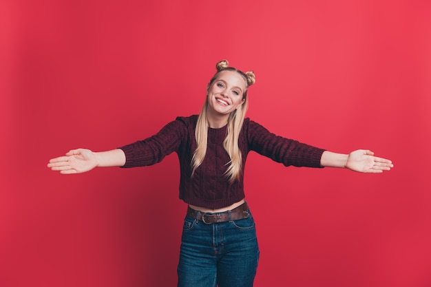 blonde woman with top-knots posing against the red wall