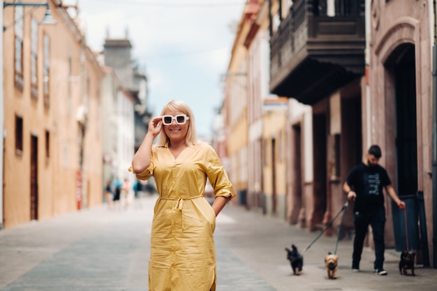 A blonde woman in a yellow summer dress stands on the street of the Old town of La Laguna on the island of Tenerife.Spain, Canary Islands