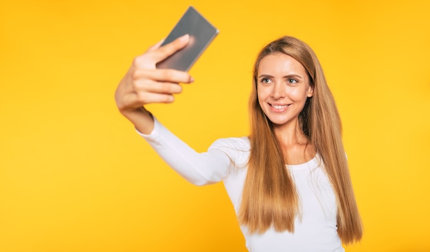 Blonde young attractive woman with smartphone. Selfie photo on cellphone. Happy picture