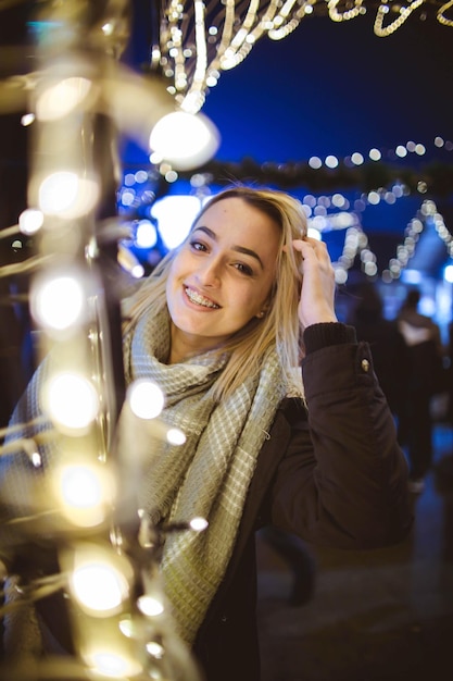 Blonde young lady posing for the camera behind the lights in the night park