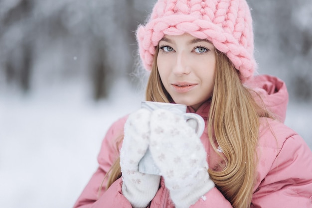 Blondie girl with cup of hot tea outdoors in winter park