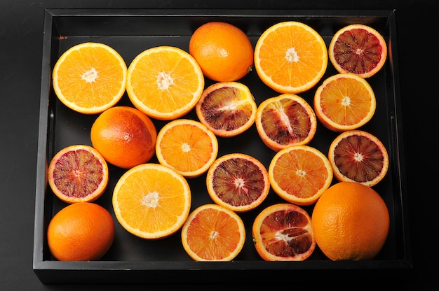 Blood oranges whole and cut in half on a black tray