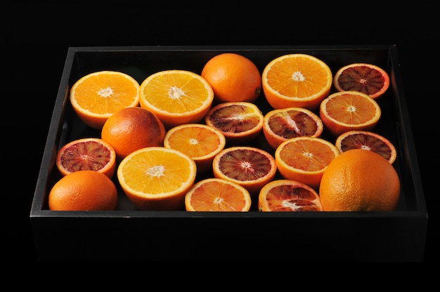 Blood oranges whole and cut in half on a black tray