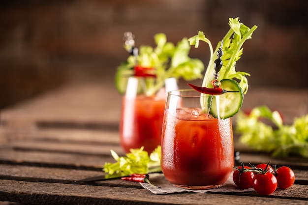 Bloody or virgin mary cocktail served in a cup with celery sticks and cherry tomatoes.