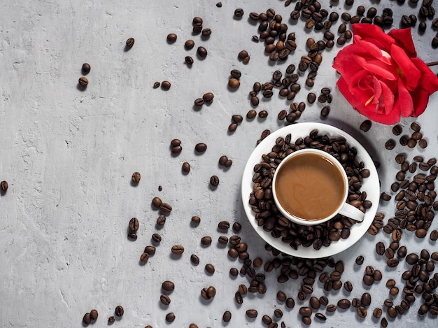 Blooming red rose coffee Cup, coffee beans on the background under the concrete.