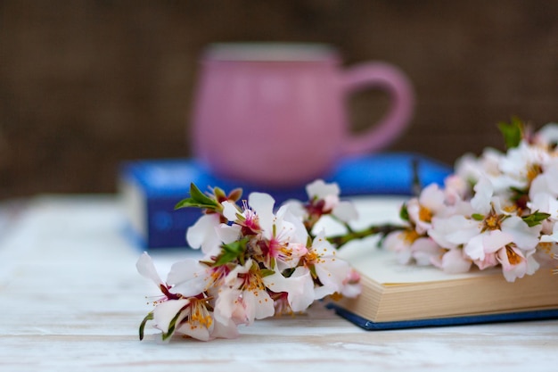 Blossom branch of almonds on a book against the background of a cup on the table