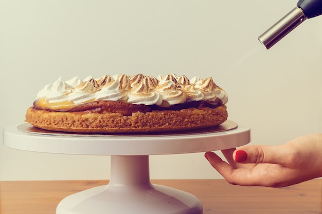 Blowtorch flambe a Carrot and Lemon Cake on white wall