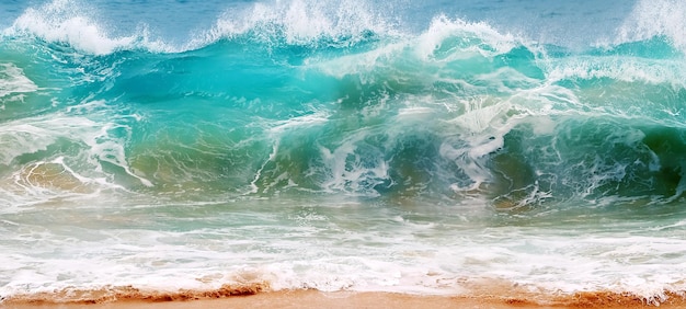 Blue and aquamarine sea waves and yellow sand with white foam Marine beach background Banner format