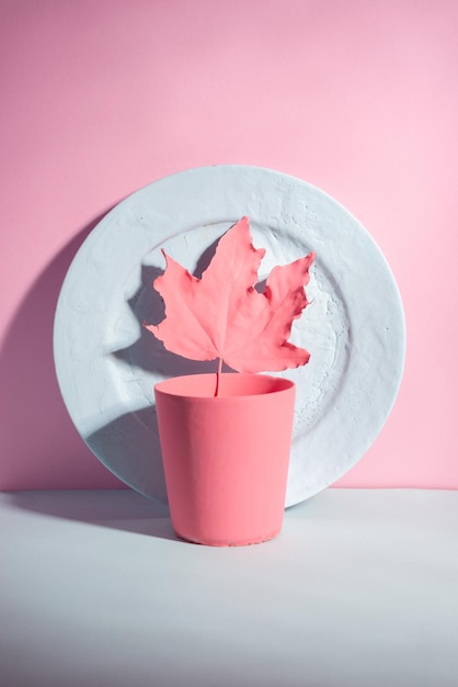 Blue autumn maple leaf on pink background minimalistic autumn still life