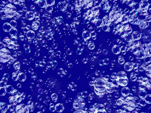 Blue background and many bubbles. Small and big bubbles float in the air.