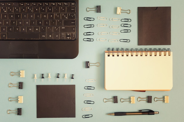 On a blue background, a notepad, paperclips and clerical buttons are neatly arranged. 