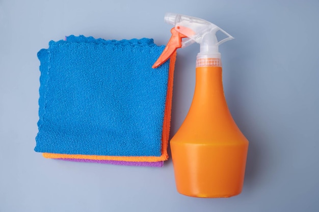 On a blue background an orange pulevizer lies next to microfiber cleaning cloths top view