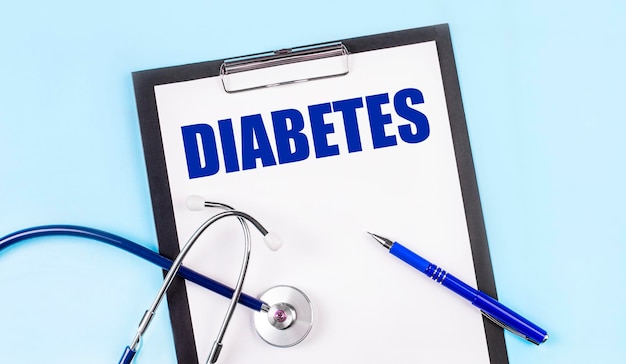 On a blue background a stethoscope a pen and a tablet with paper and the text DIABETES Medical concept