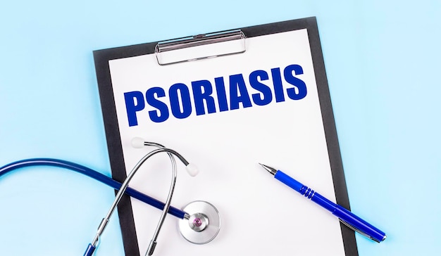 On a blue background a stethoscope a pen and a tablet with paper and the text PSORIASIS Medical concept