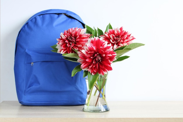 A blue backpack and red dahlias