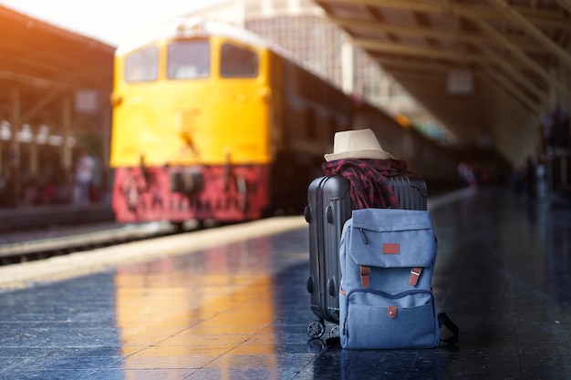 Blue backpack and scott shirt with hat on luggage, traveler suitcases in train station. Travel and Vacation concept.