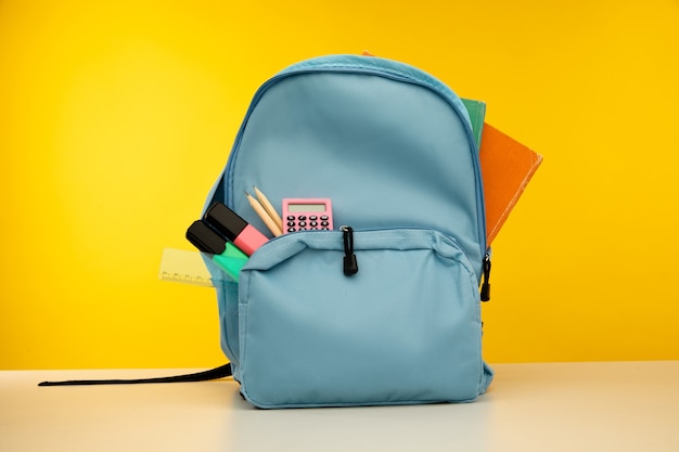 Blue backpack with different colorful stationery on table back to school