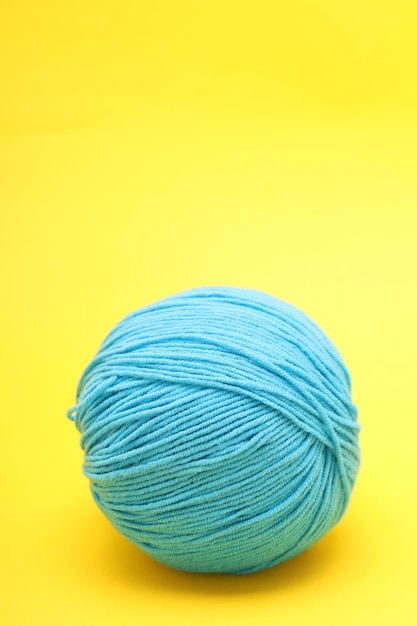 Photo blue ball of wool lies on a yellow background. high quality photo