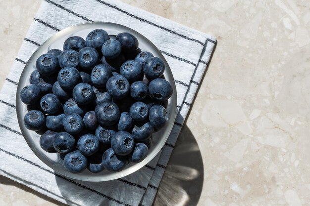 Blue blueberries in a bowl on a towel top view