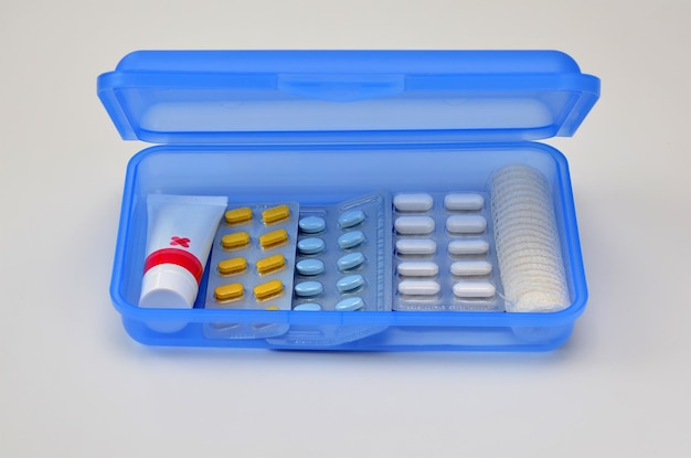 Blue box with pills and bandage on white background