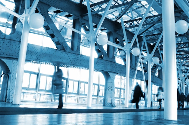 A blue building with a white ceiling and people walking in the background.