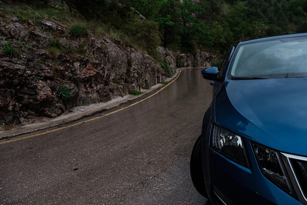 Blue car on wet road in rain at daytime