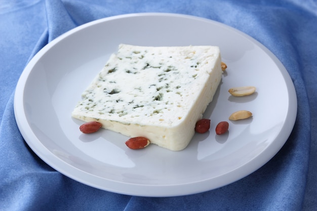 Blue cheese. Cheese on a white plate. Dairy product on a blue napkin