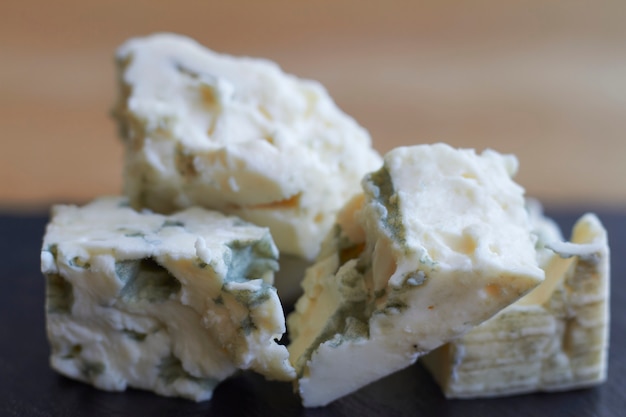 Blue cheese on wooden cutting board, pieces of soft french cheese