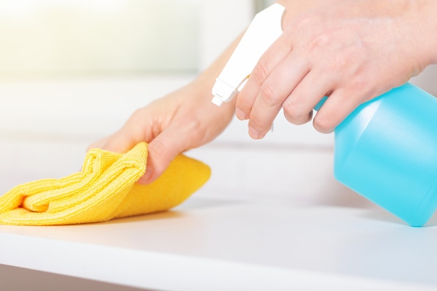 Blue chlorine bottle spray. Woman using detergent and wipe. Cleaning with cleanser spray.