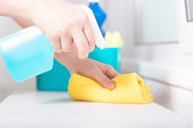 Blue chlorine bottle spray. Woman using detergent and wipe. Cleaning with cleanser spray.