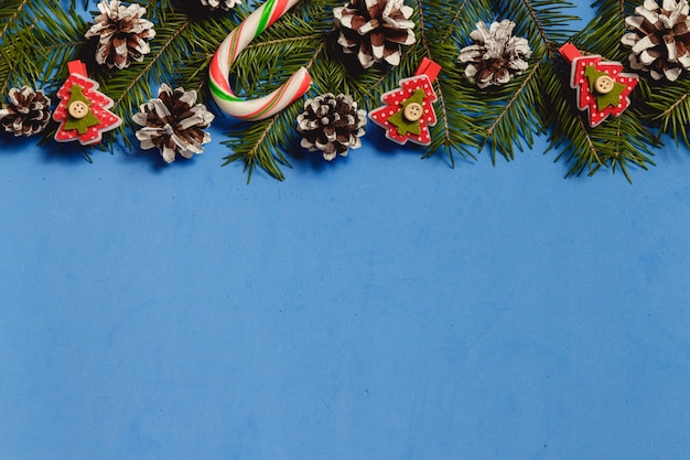 Blue christmas background with fir branches, cones, decor, top view, copyspace.