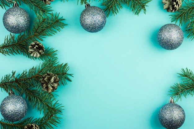 Blue Christmas background with spruce branches, cones and shiny blue balls. top view. A copy of the space for your text.