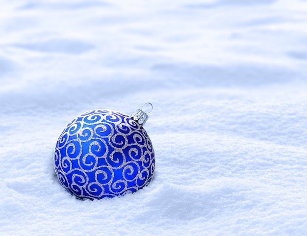 Blue christmas ball on snow. Winter background