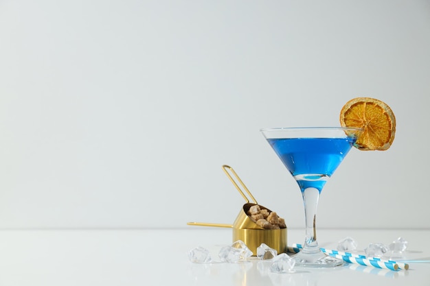 Blue cocktail in glass orange slice sugar and ice cubes on white background space for text