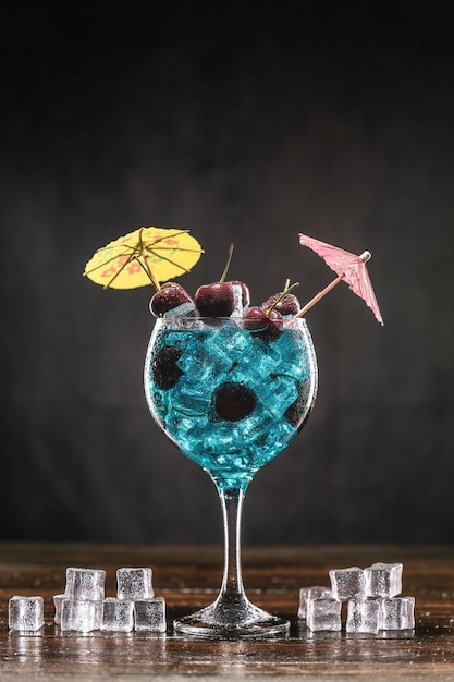 Photo blue cocktail in a glass with ice and cherries