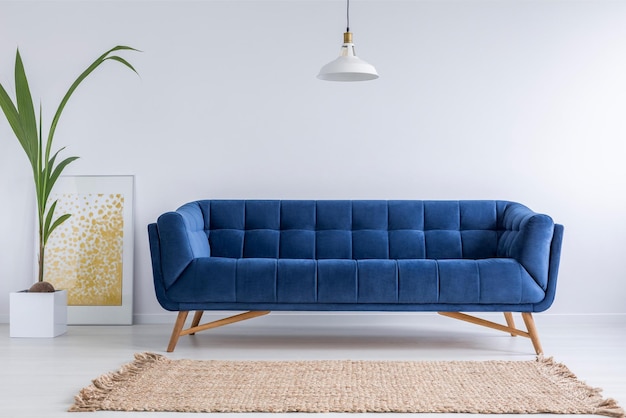 A blue couch in a living room with a plant next to it