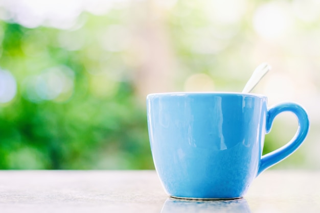 Blue cup of coffee against blurred natural background