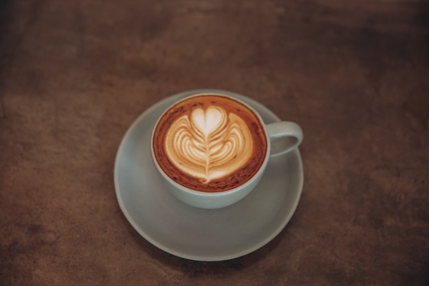 Blue cup of coffee on concrete rustic background with beautiful latte art