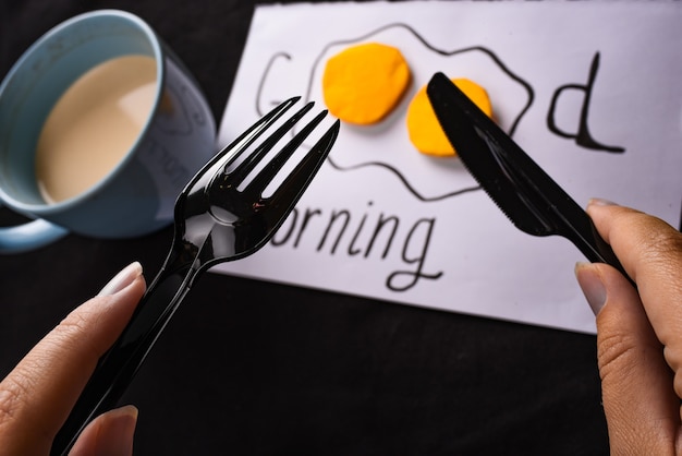 blue cup with coffee inscription good morning scrambled eggs and hands with cutlery