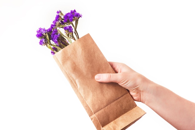 Blue dried flowers in brown paper bag in the hand on the white background Close up Top view copy space isolate